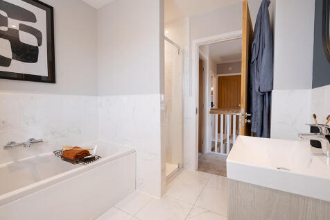 A modern, minimalist bathroom with a white bathtub, a wooden vanity