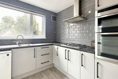 Bright kitchen with modern tiling and sleek ove...