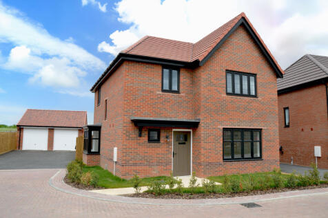 A modern brick house with black-trimmed windows stands on a paved driveway