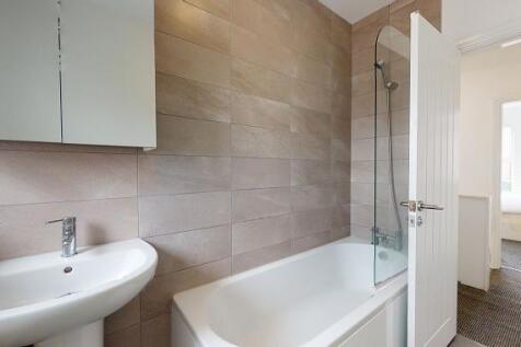 Modern bathroom with a white bathtub, glass sho...