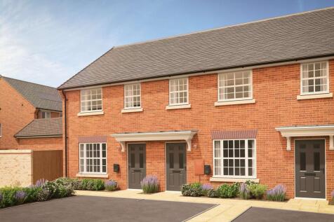 A row of modern brick townhouses with manicured gardens in the foreground stands against a clear blu