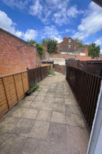 Long paved private garden with high brick walls...