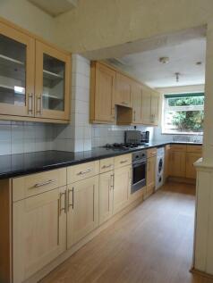 Bright galley kitchen with light wood cabinets,...