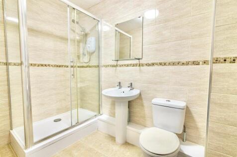 Modern tiled bathroom with a glass-enclosed sho...