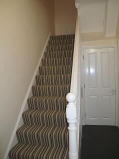 Carpeted staircase with a striped runner, white...