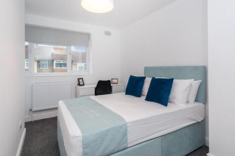 Bright, modern double bedroom with a padded hea...