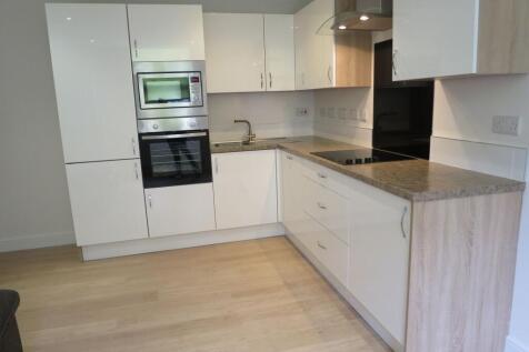 Modern kitchen featuring sleek white cabinetry,...