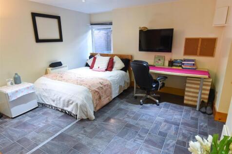 Spacious bedroom with a large desk and smart TV...
