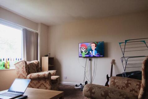 Bright lounge with wall-mounted TV and armchair...