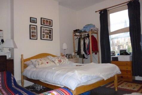 A cozy double bedroom featuring a wooden bed fr...