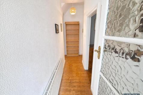 Clean hallway with wooden flooring and shelving...