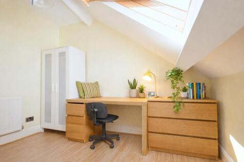 Bright, tidy attic study area with a large wood...