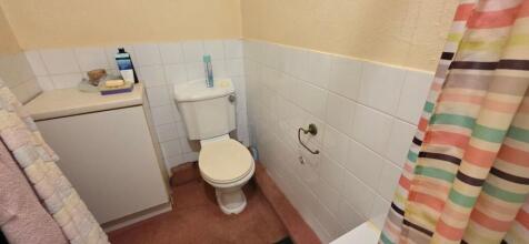 Practical tiled bathroom with storage cupboard...