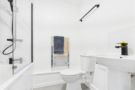 Bright, modern bathroom with a white suite, sho...