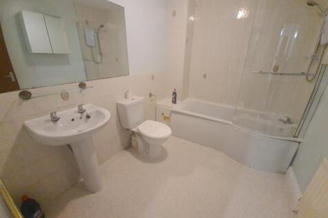 A clean and well-lit bathroom featuring a batht...