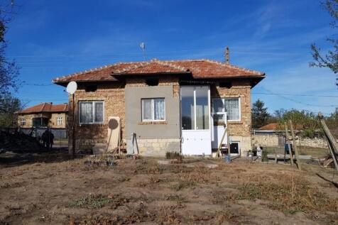 Front view of a small brick house with a tiled roof and enclosed porch in Gorotsvet village