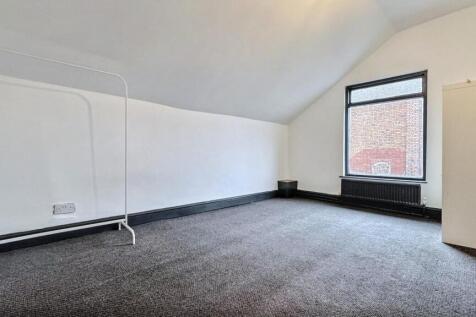 Bright, airy attic room with plush dark carpet....