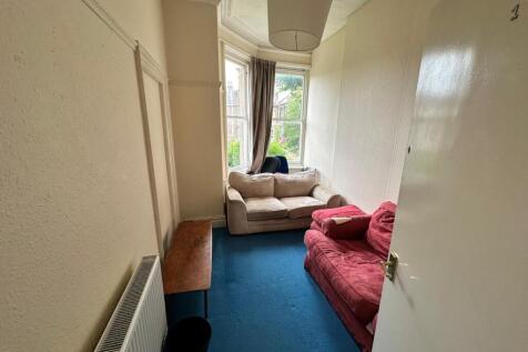 Bright communal lounge with a bay window, two c...