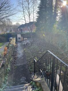 Sunny private garden with a paved pathway, matu...