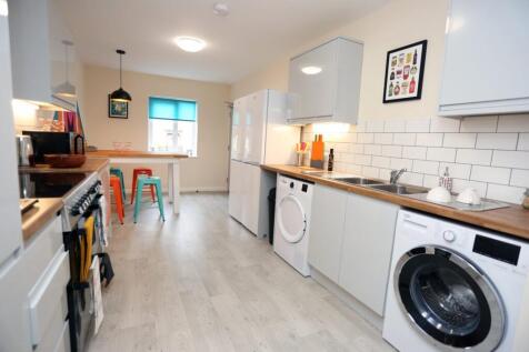 Bright modern kitchen with white cabinets, wood...