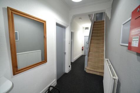 Bright, neutral hallway with carpeted stairs, f...