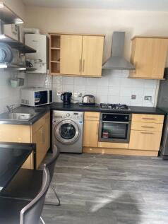 Modern fitted kitchen with pale wood cabinets, ...