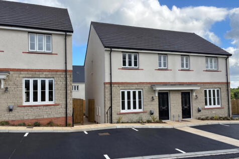 Two modern two-story houses with white and stone facades stand behind a fresh black asphalt road und
