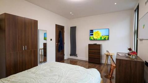 Bright, modern bedroom with warm wooden furnitu...