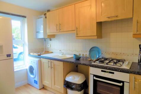 Bright and tidy kitchen featuring light wood ca...