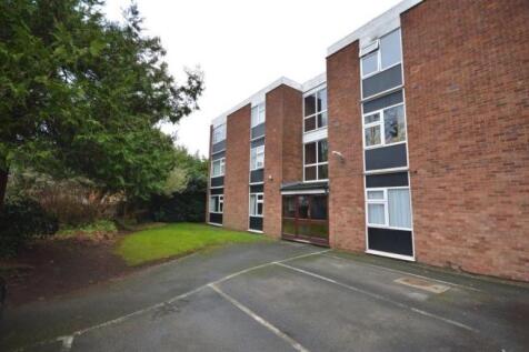 Modern brick building with green lawn and parki...