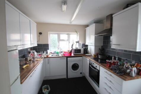 Modern galley kitchen with white cabinets, wood...