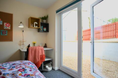 Bright, neatly styled bedroom with sliding glas...