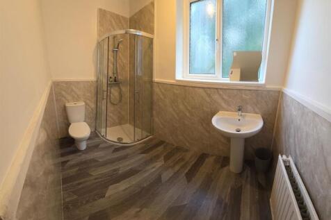 Bright modern bathroom with a corner glass show...