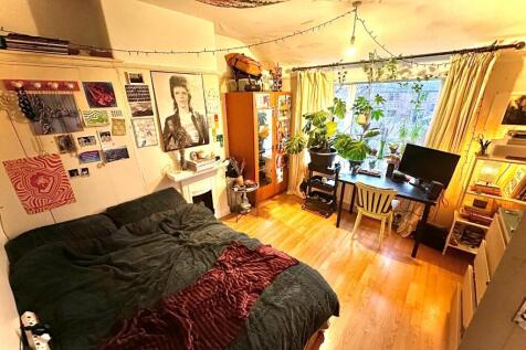 Bright, cozy bedroom with large window, abundan...