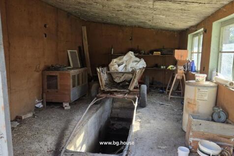 Outdoor outbuilding containing various tools, equipment, and a vehicle inspection pit in the floor.