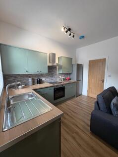 Modern fitted kitchen with sage-green cabinets,...