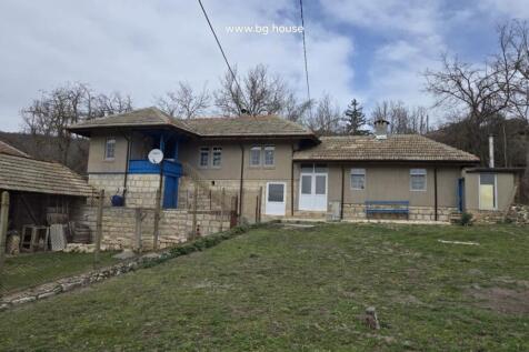 Front view of a traditional Bulgarian house with stone foundation and tiled roof in Kostandenets village