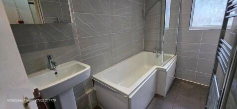 Modern bathroom with sleek grey tiling and bath...