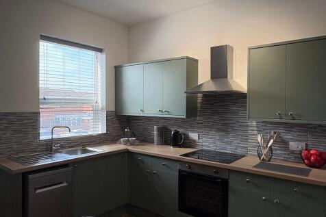 Modern fitted kitchen with pale green cabinetry...