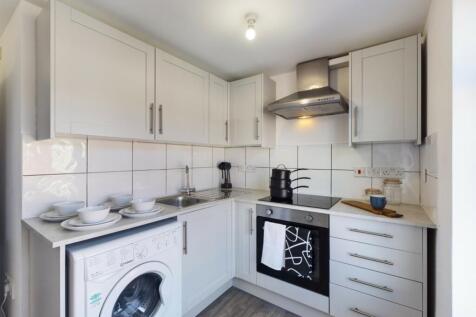 A modern and tidy kitchenette with ample storag...
