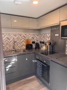 Modern fitted kitchen with glossy grey cabinets...