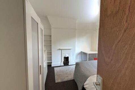 A cozy bedroom featuring a small fireplace, a w...