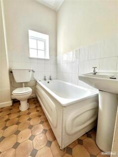 Bright bathroom with bath and natural window li...