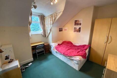 A cozy bedroom featuring a single bed with a br...