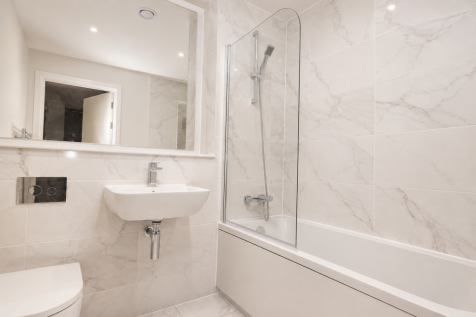 Modern bathroom with full-size bath, shower over and marble-effect tiling