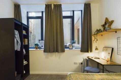 Bright, simply furnished bedroom with two tall ...