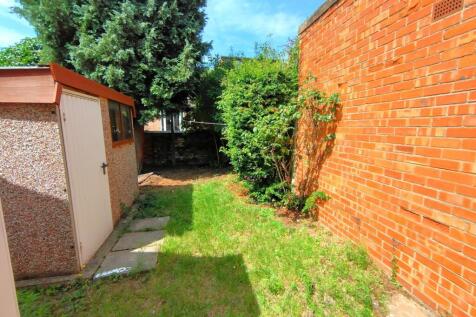 Sunny enclosed rear garden with lawn, mature sh...