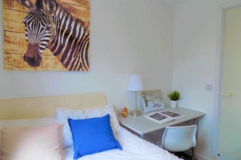 A cozy single bedroom featuring a clean, white ...