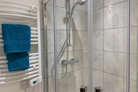 Modern tiled bathroom with a glass-enclosed sho...