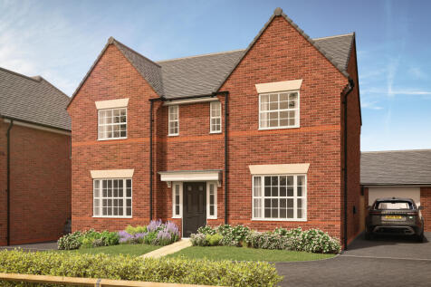 A red brick house with manicured bushes and flowers in the foreground sits under a bright blue sky w